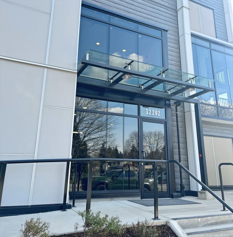 Curtain wall glazing and aluminum entrance door at an Abbotsford multi-unit residential building.
