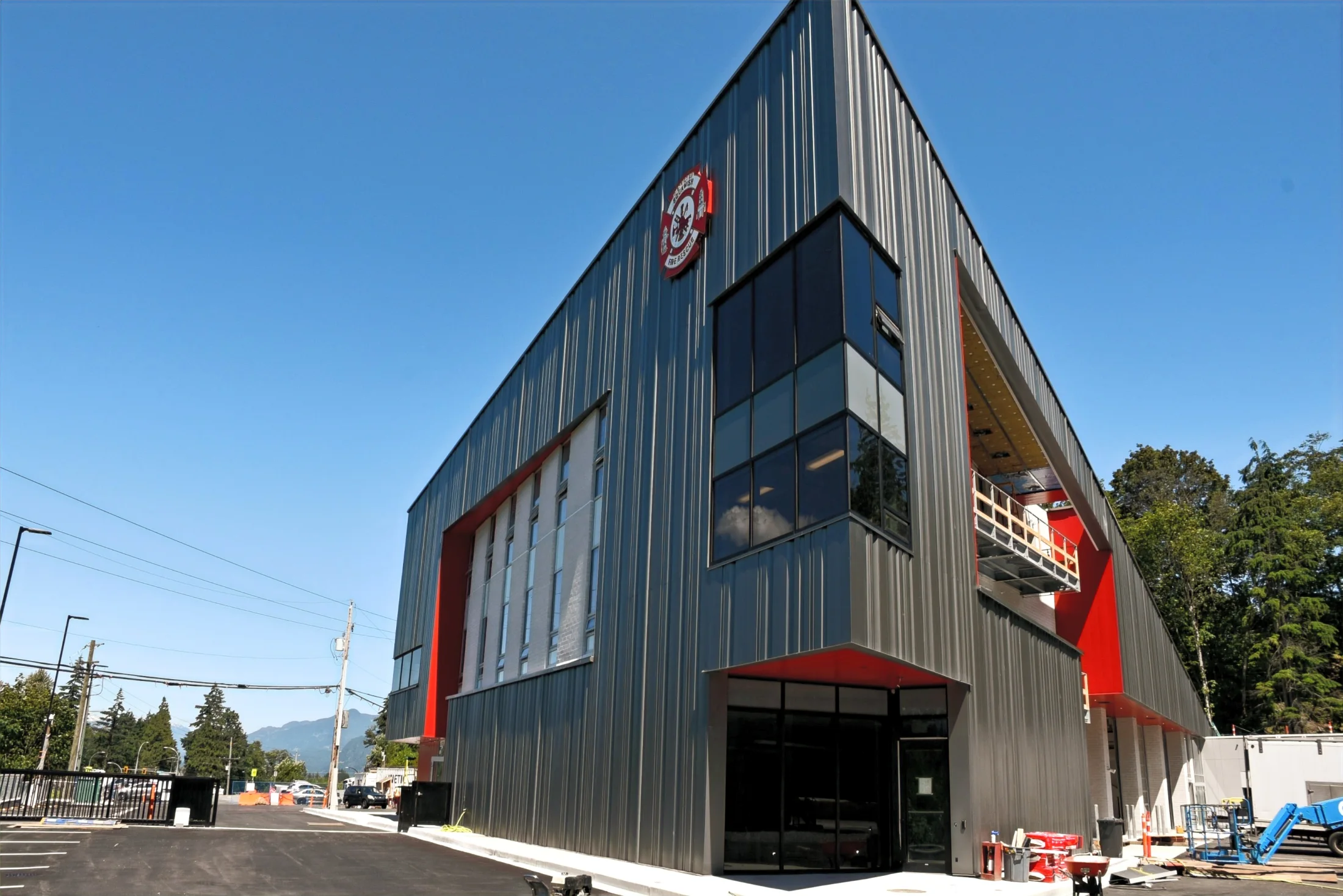 Squamish Fire Hall — Tall corner glazing brings a transparent edge to the dark-clad fire hall, contrasting with its red accents.