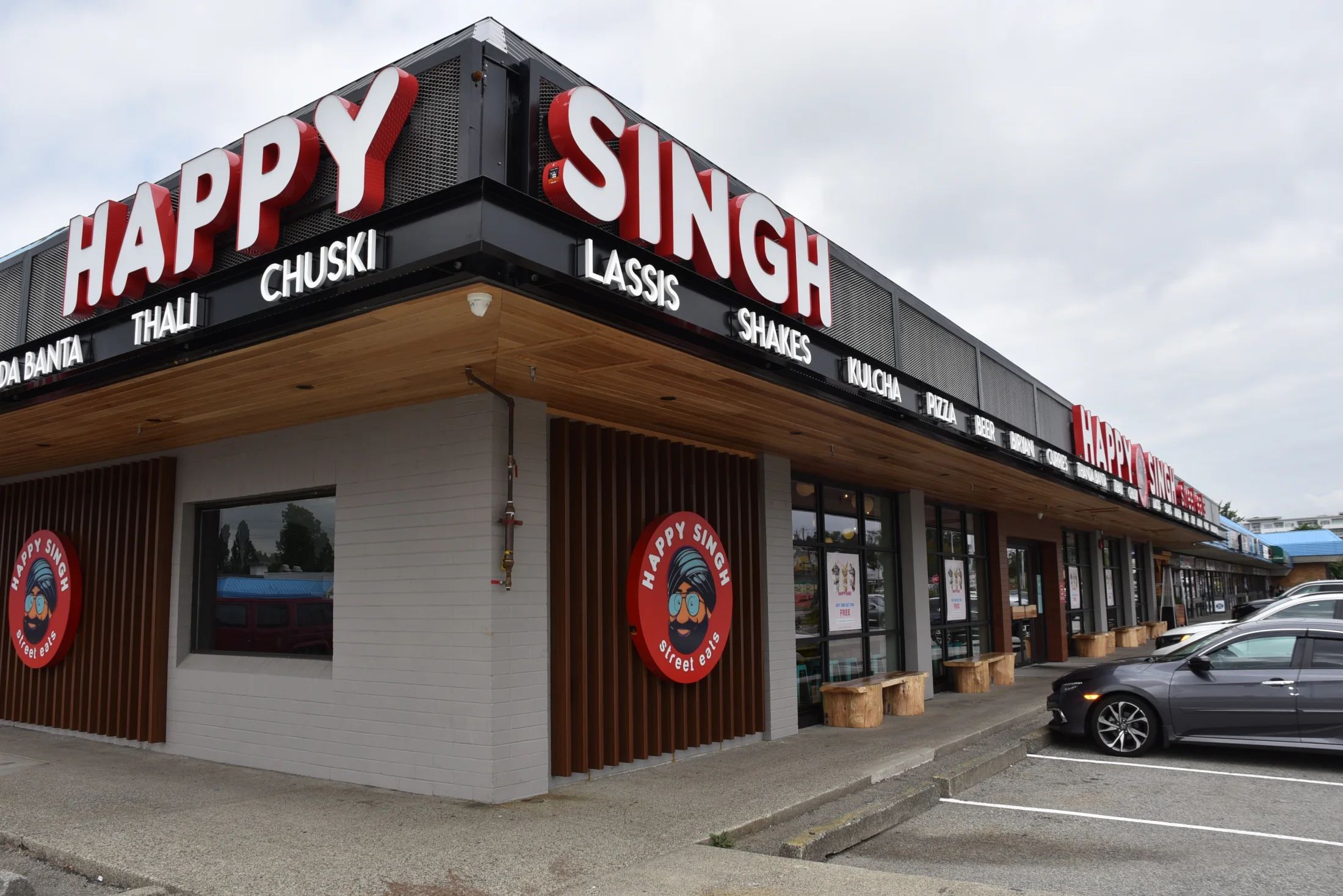 Happy Singh Storefront — A continuous glazed frontage connects the restaurant entrance with the surrounding pedestrian walkway.