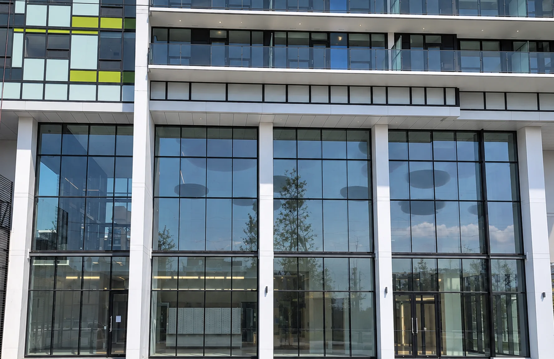 Tailor by Marcon: Tall lobby glazing and entrance doors beneath the residential balconies.